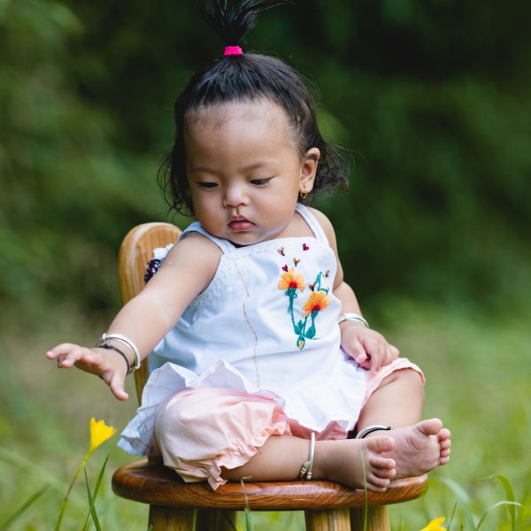 Baby girl reaching for a flower